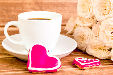 Valentine's day. Wedding . A Cup of coffee and two gingerbread heart on a background of roses.