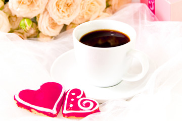 Valentine's day. Wedding . A Cup of coffee and two gingerbread heart on a background of roses