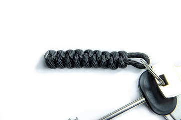 Paracord, weaving rope rope, trinkets lanyards knots. Paracord for tourism and survival. Lanyard on keys and a flash drive on a white background