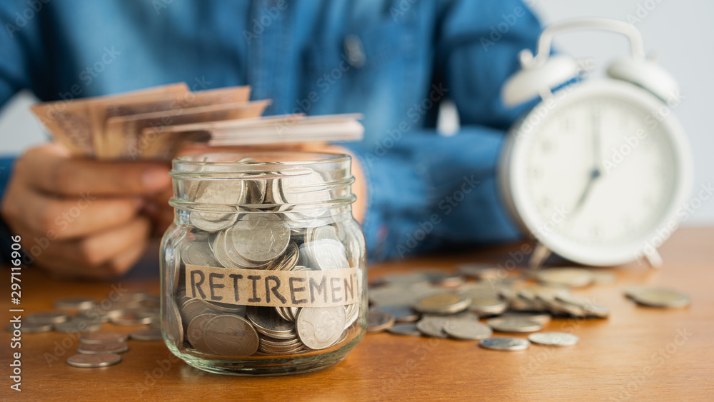 Wall mural coin in a glass bottle image blurred background of business people sitting counting money and a retr