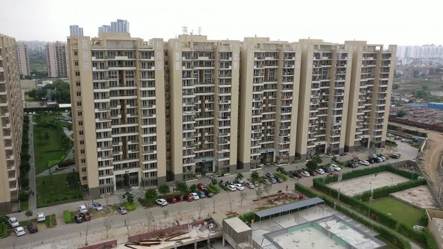Aerial shot of skyscrapers with multiple floors and flats which house families, with parkings on teh ground floor and beautiful grounds