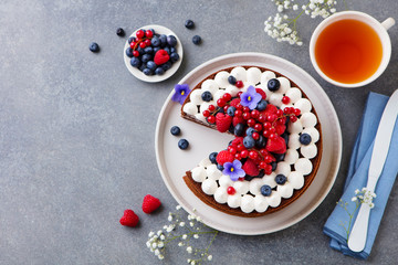 Chocolate cake with whipped cream and fresh berries. Grey background. Top view. Copy space.