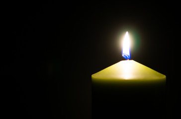 Beautiful flame on green candle in the dark. Copyspace for text