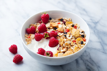 Healthy breakfast. Fresh granola, muesli with yogurt and berries. Marble background. Close up.