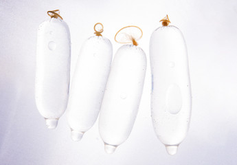 Closeup of condoms filled with water, on a white background.