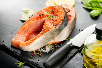 Salmon. Raw Trout Red Fish Steak served with Herbs, Lemon and olive oil on slate. Cooking Salmon, sea food. Healthy eating concept, Mediterranean cuisine 