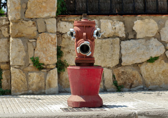 Fototapeta na wymiar Old red fire hydrant on the street, looks like a face, funny face