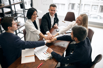 happy cheerful co-workers keeping hands together, close up photo. teamwork, friendship