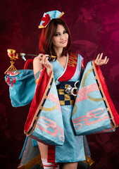 Naklejka premium Beautiful leggy busty cosplayer girl wearing a stylized Japanese kimono costume cheerfully posing holding a fake pipe on a blue background.