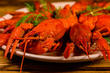 Plate with boiled crayfishes on wooden table