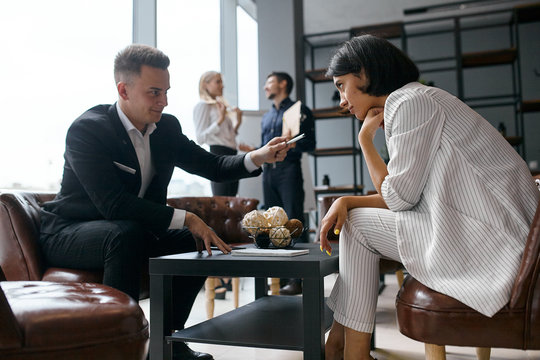 cunning businesswoman asking woman to sign the documant, sly business plan, man giving a pen to puzzled brunette woman who is hesitating to write on the notepad.
