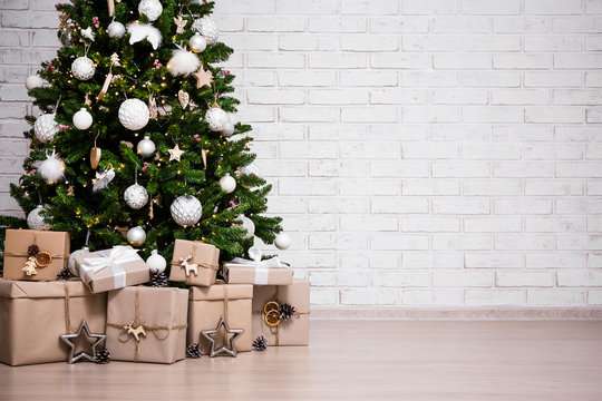 decorated christmas tree and gift boxes over white brick wall with copy space