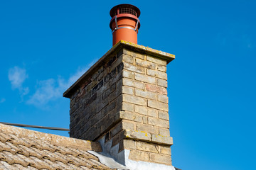 Large, english cottage style brick chimney showing a newly installed terracotta pot together with a...