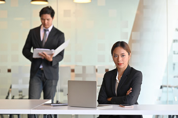 Confident young businesswoman sitting on business workplace with team.