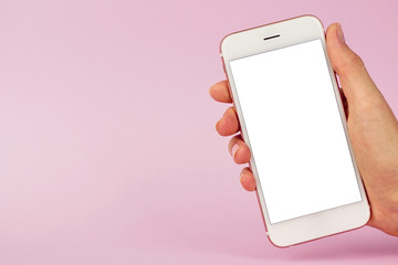Mobile phone in female hand on pink background, minimal technology concept