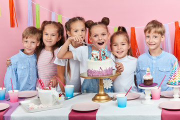 positive kids looking forward to taste dessert, posing to the camera. isolated pink background, studio shot