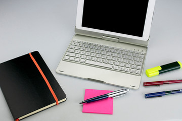 Office supplies consisting of tablet with keyboard, fluorescent marker, red and blue markers, modern pen, sticky notepad and note book