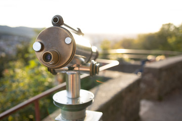 Münzfernrohr blickt in den Sonnenuntergang auf die Stadt