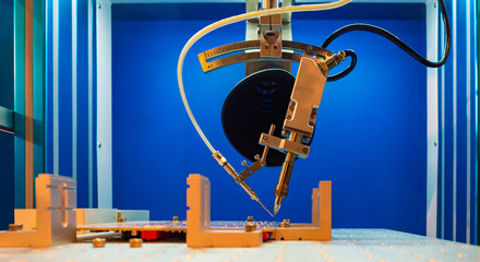 Fototapeta na wymiar Robotic soldering iron for electronic circuit boards on blue . Automation of production of printed circuit boards. Radionics. Equipment for PCB soldering.