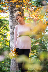 Young pregnant woman in nature enjoying autumn sun outdoors.