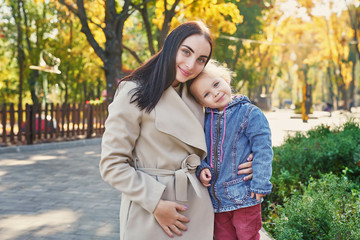 Happy family on autumn walk. Mother and daughter walking in Park and enjoying beautiful autumn nature. Hello, Autumn! Happy loving family having fun. Autumn leaf fall