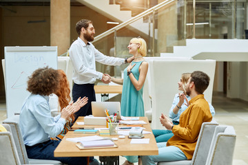 Impressed satisfied man with thick beard and optical spectacles, gives gentle handshake to charming lady in beautiful green dress, woman keeps hand on heart with pleasant smile
