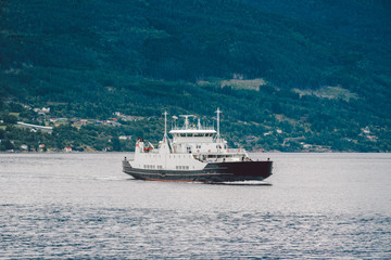 Fototapeta na wymiar Ferry boat transportation Norway. White passenger ferry goes on fjord. In Norway. ferry crossing a fjord. Ferryboat cruising on Norwegian fjord