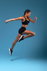 professional athlete training at sport center, full length side view photo. isolated blue background, studio shot.health and body care, wellness, woman is running to her dream - obrazy, fototapety, plakaty