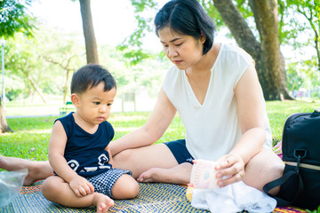 Mom playing with baby boy in city green park