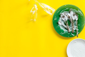 Washing dishes concept. Plates, spoons, forks on yellow background top view copy space