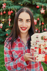 Family Christmas in July. Portrait of girl near christmas tree with gifts. Decorating pine. Winter holidays and people concept. Merry Christmas and Happy Holidays Greeting card. Christmas woman