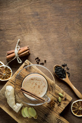 Masala chai tea in one glass Cup on wooden background in rustic style. Traditional Indian drink with milk, black tea and spices. Copy space, top view.