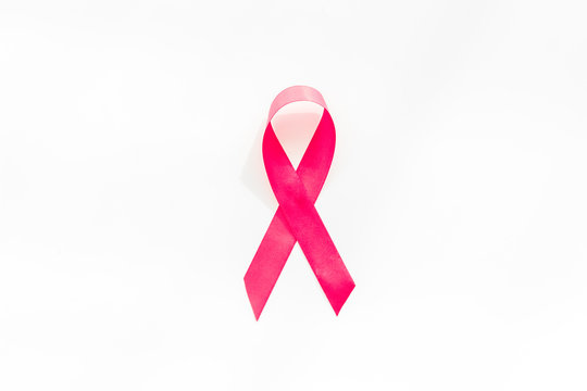 Pink ribbon as symbol of breast cancer awareness on white background top view copy space