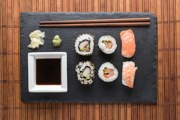 Sushi pieces, soy sauce, ginger and wasabi, and wooden chinese chopsticks top view