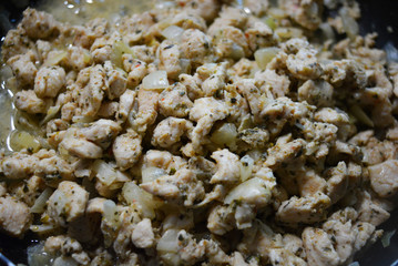 Finely chopped pieces of homemade chicken breast, fried and stewed with onions and sunflower oil. Slices of delicious, juicy chicken lying on a black skillet while frying.