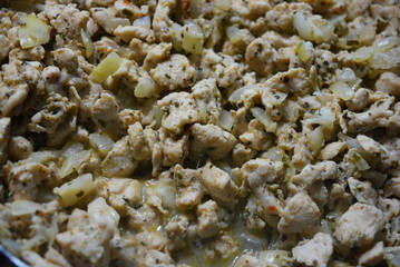 Finely chopped pieces of homemade chicken breast, fried and stewed with onions and sunflower oil. Slices of delicious, juicy chicken lying on a black skillet while frying.