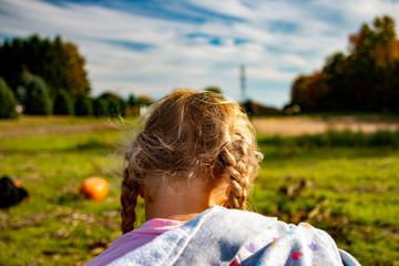Fall themed photo of a little girl in a pumpkin patch