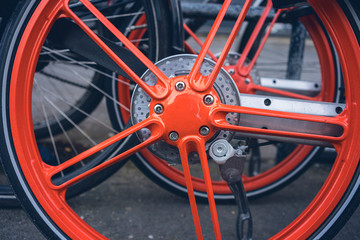 close up a orange rim of a bicycle for rent
