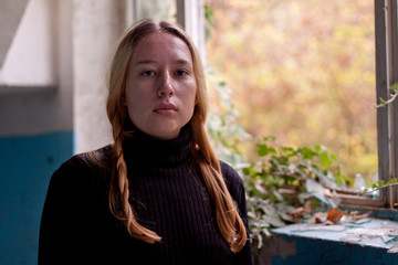 sad girl near the window in an old house