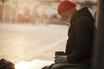 Mature beggar man looking hopefully at rusty empty jar, waiting for money help. Poverty, hunger...