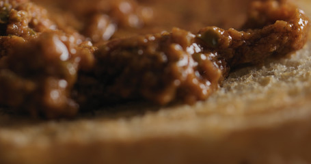 Extreme closeup spread red pesto on ciabatta slice