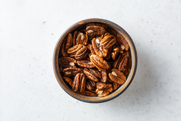 Peeled pecan halves in a bowl, on white background. Close up,Top view.