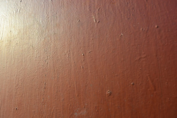 Old metal building sheet covered with brown paint with a golden tint in bright sunlight. Interesting structure and texture with gilding.
