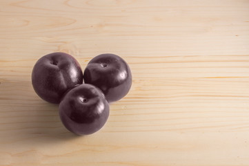 three plums isolated on wooden background