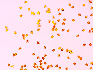 Pink background with golden stars, copy space. Golden stars confetti on pastel background.