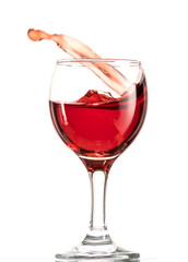 a splash of red wine in a glass on a white background