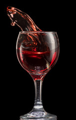 a splash of red wine in a glass on a black background