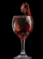 a splash of red wine in a glass on a black background