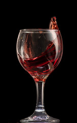 a splash of red wine in a glass on a black background