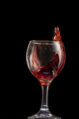 a splash of red wine in a glass on a black background